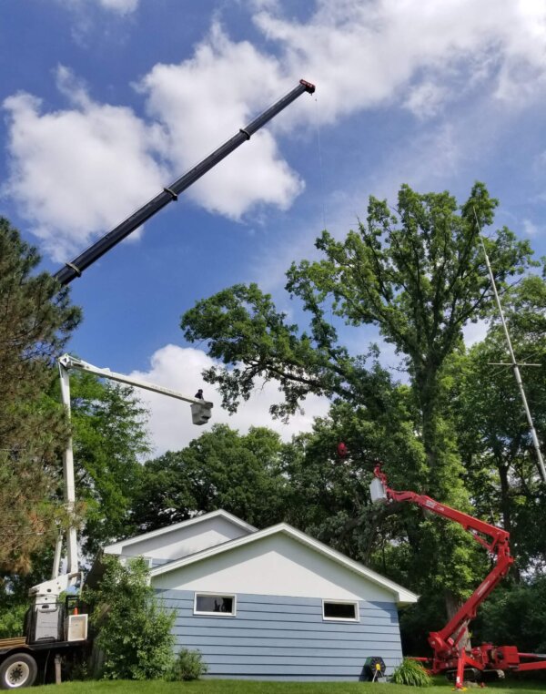 Multiple tree cranes removing hazardous tree right above residential home.